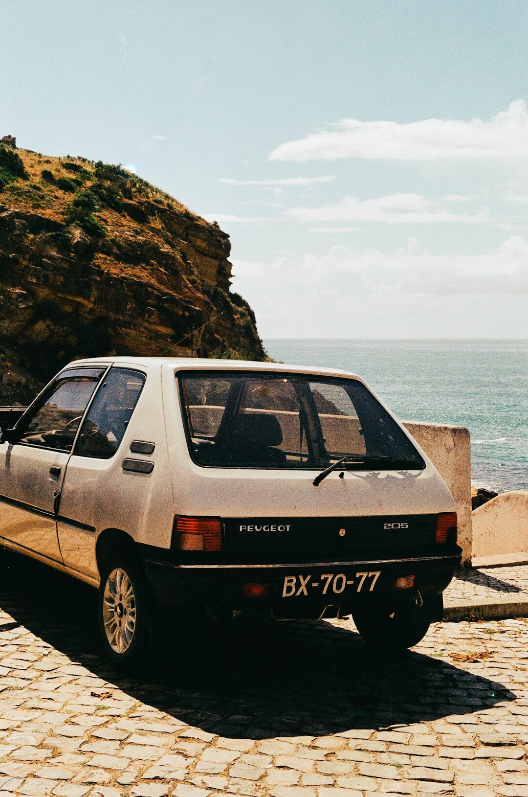 Vintage sports car driving along a coastal road at sunset in Punta del Este